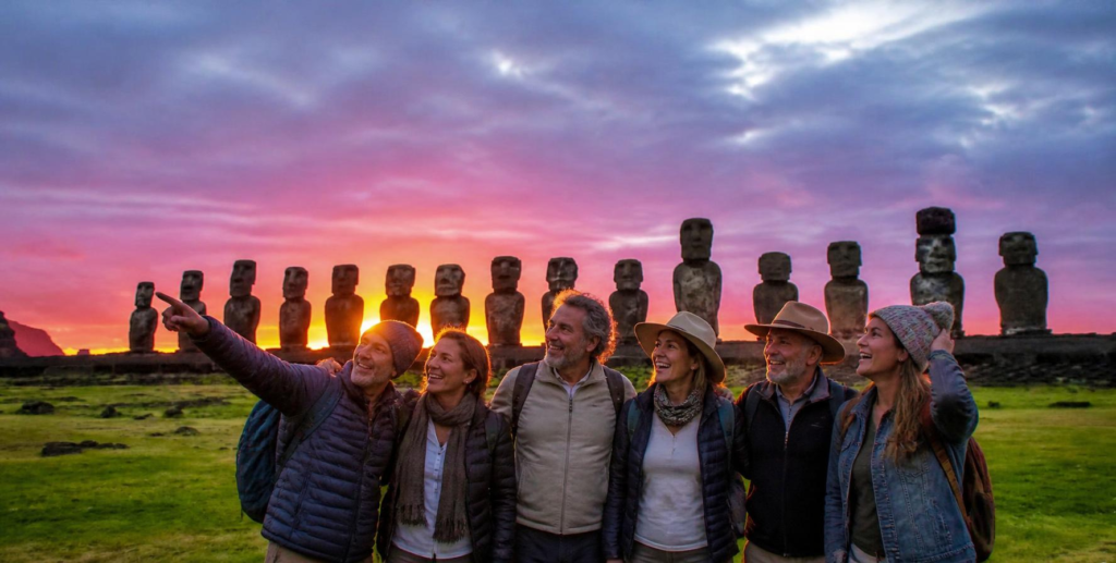 Grupo de viajeros sonriendo frente a los moáis de Ahu Tongariki al amanecer en Rapa Nui