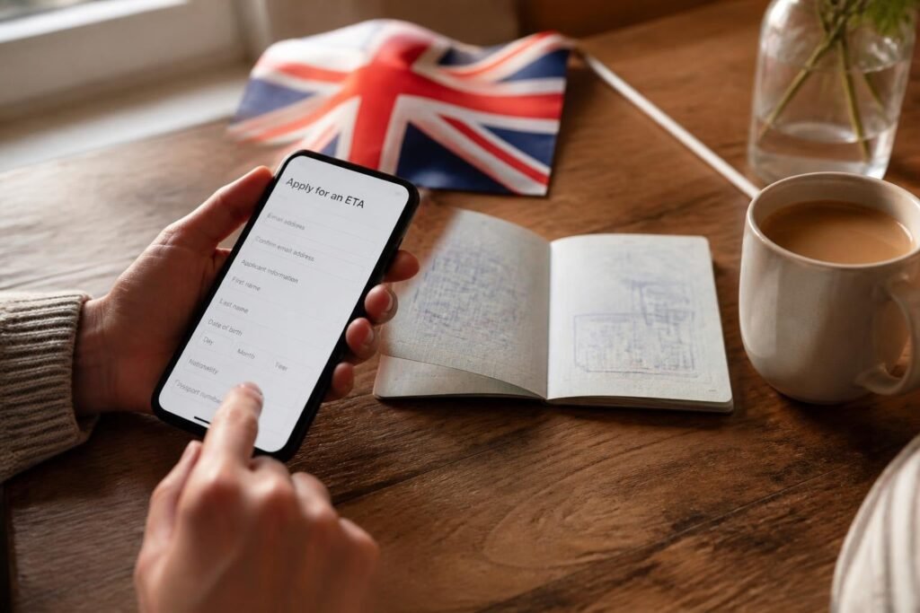 Persona tramitando la ETA del Reino Unido desde su celular junto a su pasaporte Persona tramitando la ETA del Reino Unido desde su celular junto a su pasaporte